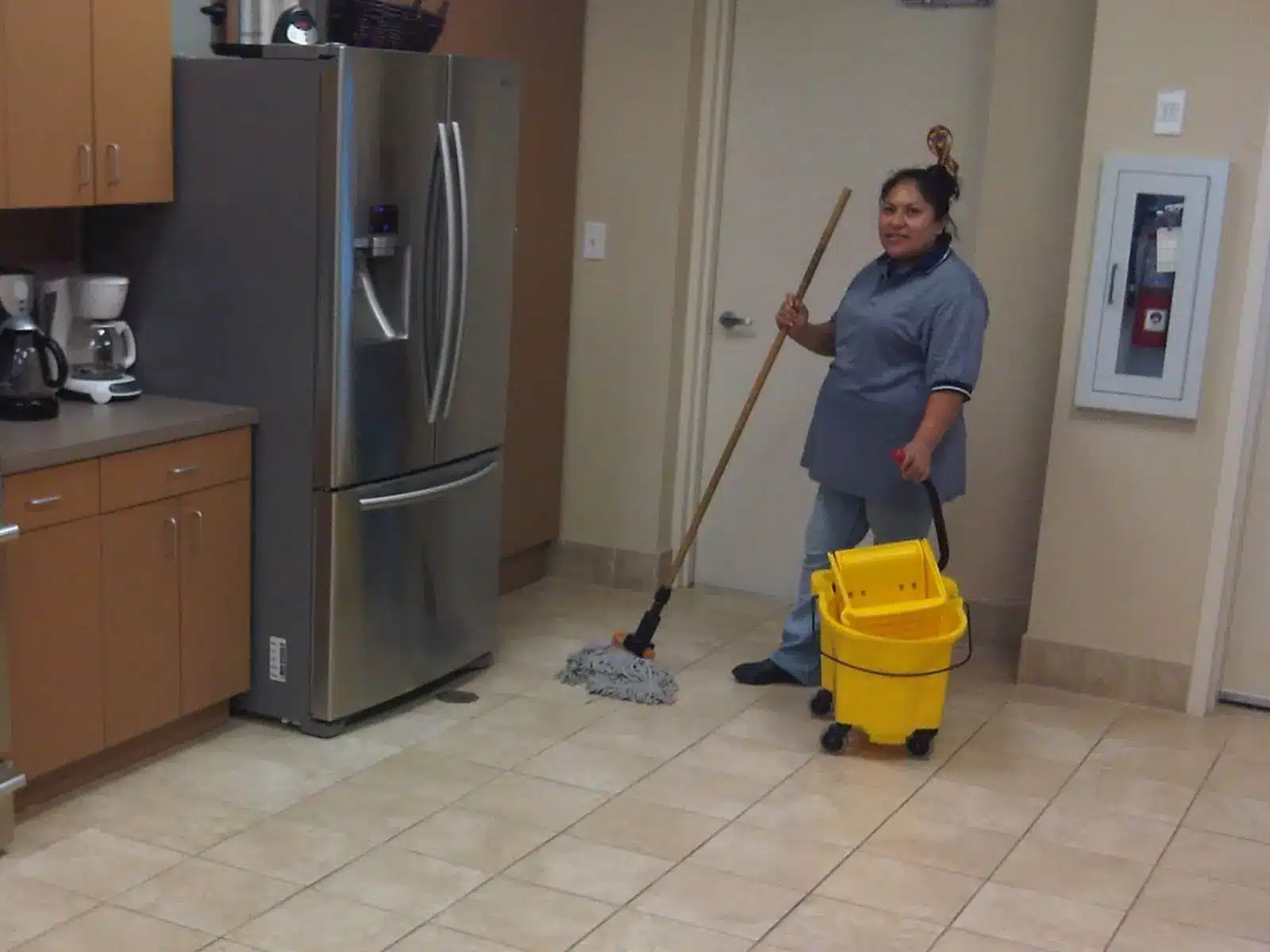 Small office cleaning in Allen, TX: cleaner mopping a breakroom floor next to the refrigerator and coffee station